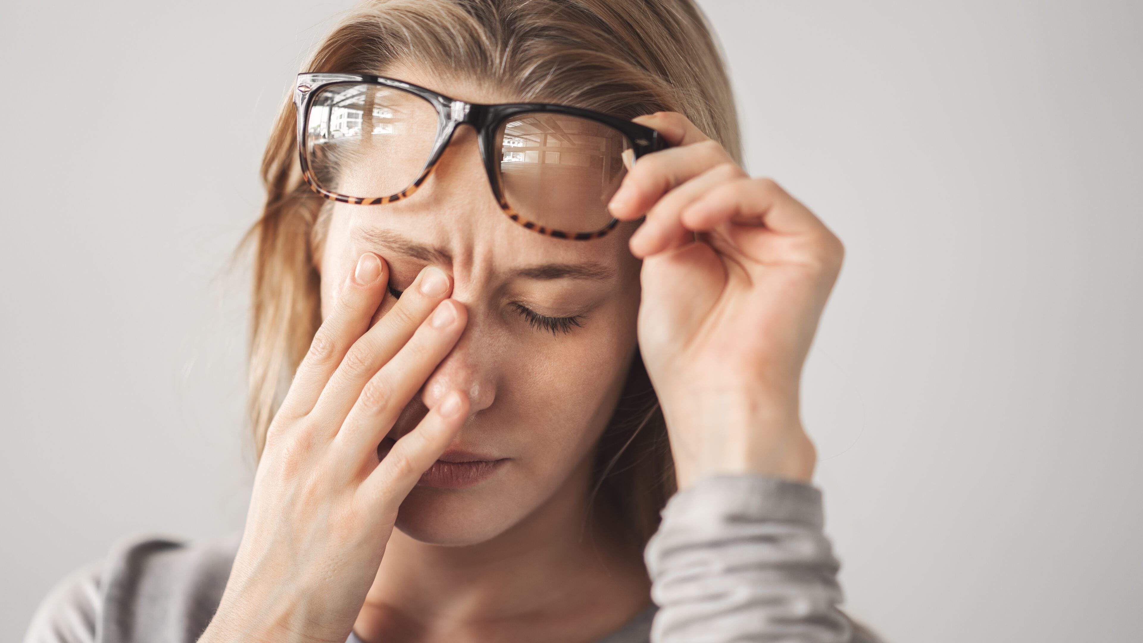 Woman rubbing eyes with glasses lifted